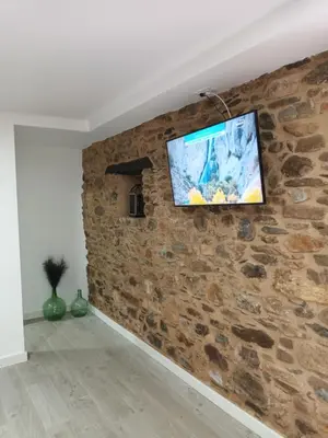 a flat screen tv hanging on a stone wall at Él Rincón de los Sueños A in Vegadecabo