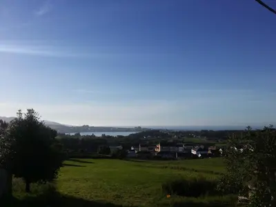 a green field with a lake in the distance at Apartamentos A Palleira in Barreiros