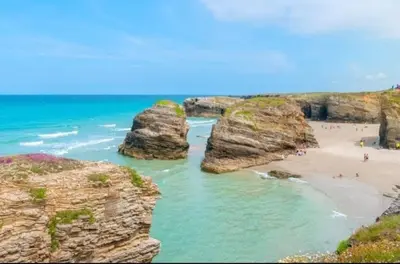 people on a beach with large rocks in the ocean at House Borba Foz in Foz