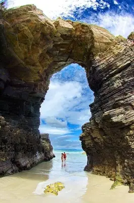 two people standing in the water under a rock formation at Tranquilidad cerca de playas y lugares históricos VUT-LU-00402 in Lourenzá