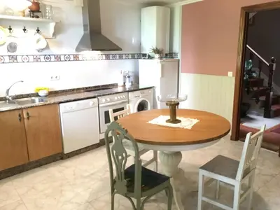a kitchen with a wooden table with chairs and a sink at Tranquilidad cerca de playas y lugares históricos VUT-LU-00402 in Lourenzá
