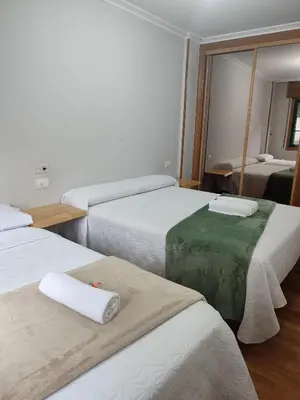 a hotel room with three beds and a mirror at Pensión Armonía in Caldas de Reis