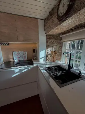 a kitchen with a sink and a clock on the wall at A Palleira in San Amaro