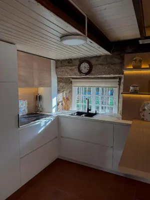 a kitchen with a sink and a clock on the wall at A Palleira in San Amaro