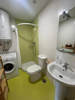 a bathroom with a toilet and a sink and a washing machine at Acogedor playa grande Miño in Miño