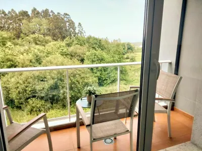 a balcony with two chairs and a table and a window at El Valle in San Cosme de Barreiros