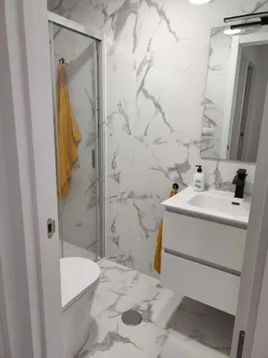 a white bathroom with a shower and a sink at Piso en Valadouro in Valle de Oro