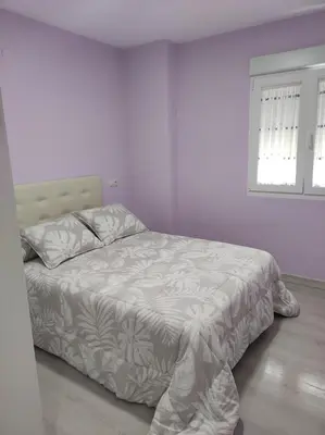 a bedroom with a bed with a white comforter and a window at Piso en Valadouro in Valle de Oro