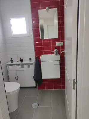 a red tiled bathroom with a toilet and a sink at Piso en Valadouro in Valle de Oro