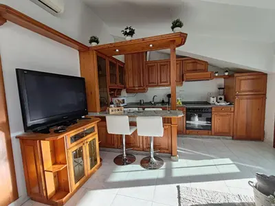 a kitchen with wooden cabinets and a flat screen tv at Loft Luxury in Caldas de Reis