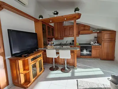 a kitchen with wooden cabinets and a flat screen tv at Loft Luxury in Caldas de Reis