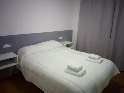 a white bed with two towels on top of it at Adrian in Arzúa
