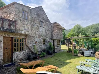 a stone house with a yard with picnic tables at Casa Aradiña in Santa María