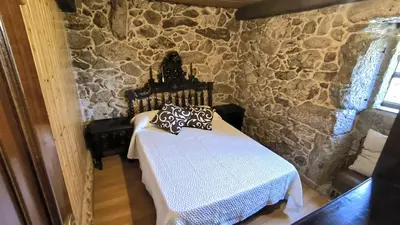 a bedroom with a bed in a stone wall at Casa Aradiña in Santa María