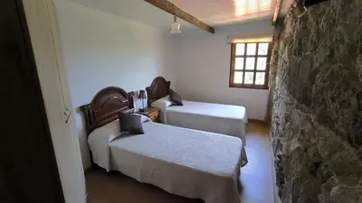 a room with two beds and a stone wall at Casa Aradiña in Santa María