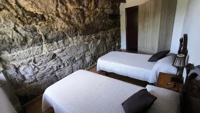 a room with two beds and a stone wall at Casa Aradiña in Santa María