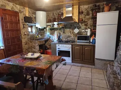 a kitchen with a table and a white refrigerator at Casa Aradiña in Santa María