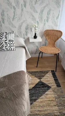 a bedroom with a bed and a rattan chair at Rua Nova in Sarria