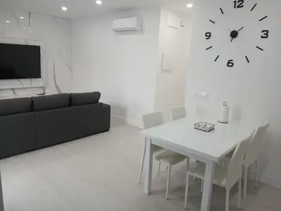 a living room with a table and a clock on the wall at Alojamiento FCB Rúa Nova in O Pedrouzo