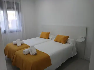 two beds with orange and white sheets in a room at Alojamiento FCB Rúa Nova in O Pedrouzo