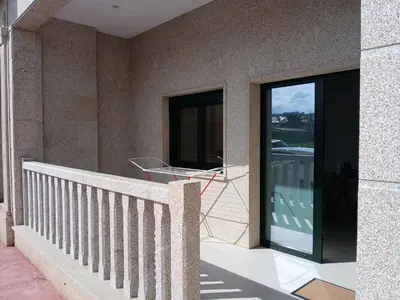 a balcony of a house with a glass door at Alojamiento FCB Rúa Nova in O Pedrouzo