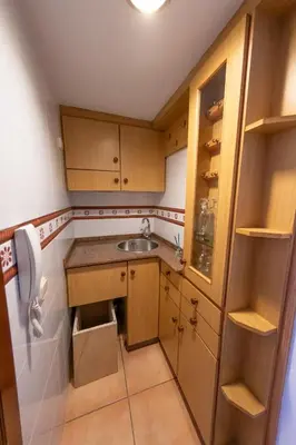 a small kitchen with wooden cabinets and a sink at Duplex en Burela Mi Piso 90 in Burela de Cabo
