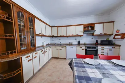 a kitchen with white cabinets and a table with red chairs at Duplex en Burela Mi Piso 90 in Burela de Cabo