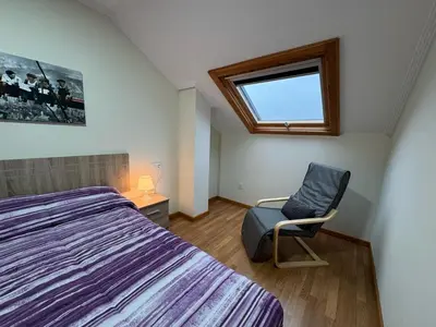 a bedroom with a bed and a chair and a window at Apartamento en Barreiros in San Miguel de Reinante