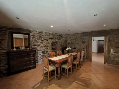 a dining room with a table and chairs and a stone wall at Casa Brandelos in Bama