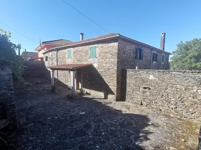 a stone building with an awning next to a stone wall at Casa Brandelos in Bama