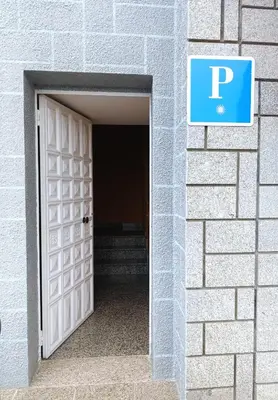 an open door into a brick building with a parking sign at Pensión Prieto in Junquera de Espadañedo