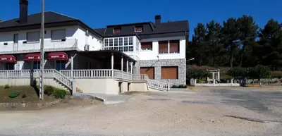 a large white building with a driveway in front of it at Pensión Prieto in Junquera de Espadañedo