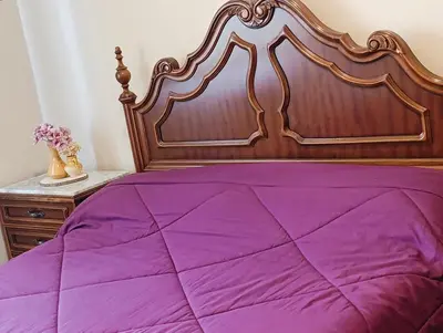 a purple bed with a wooden headboard and a table at Pensión Prieto in Junquera de Espadañedo