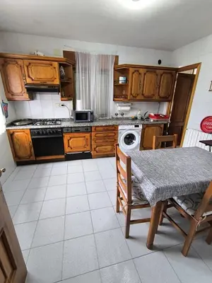 a kitchen with wooden cabinets and a table and a stove at Casa familiar Sanabria in Ribadelago