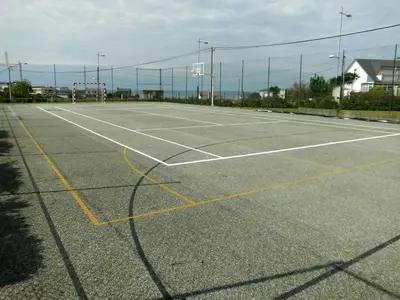 an empty tennis court with a net at Zona Las Catedrales Barreiros Playa de Altar in Villadaíde