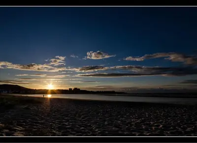 a sunset on a beach with the sun in the sky at Zona Las Catedrales Barreiros Playa de Altar in Villadaíde