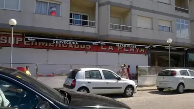 two cars parked in a parking lot in front of a building at Zona Las Catedrales Barreiros Playa de Altar in Villadaíde