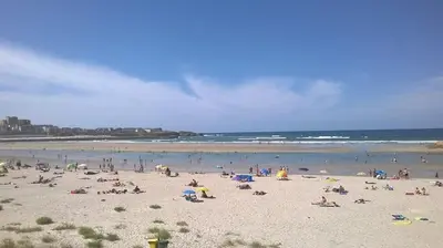 a large group of people on a beach at Zona Las Catedrales Barreiros Playa de Altar in Villadaíde