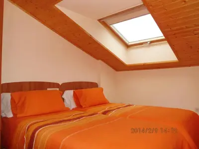 a bedroom with a bed with orange sheets and a skylight at Zona Las Catedrales Barreiros Playa de Altar in Villadaíde