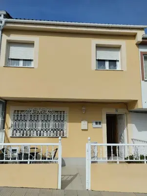 a yellow house with chairs on a balcony at Casa María in Ribadeo
