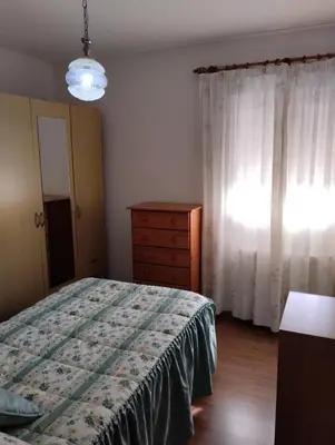 a bedroom with a bed and a dresser and a window at Casa María in Ribadeo