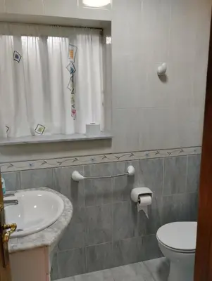 a bathroom with a sink and a toilet and a window at Casa María in Ribadeo
