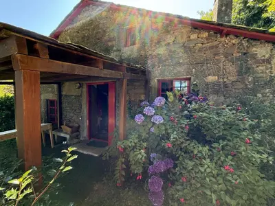 an old stone house with flowers in front of it at O Freixo in A Capela