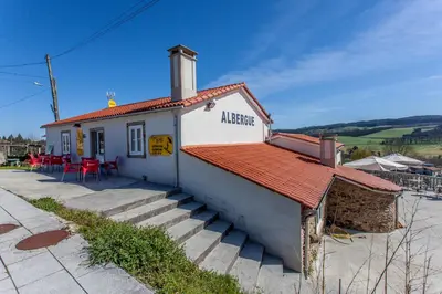 a small white building with a red roof at Albergue Milpés in Ribadiso