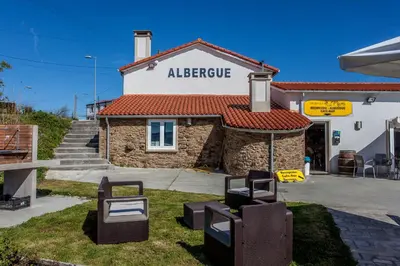 a building with two wicker chairs in front of it at Albergue Milpés in Ribadiso