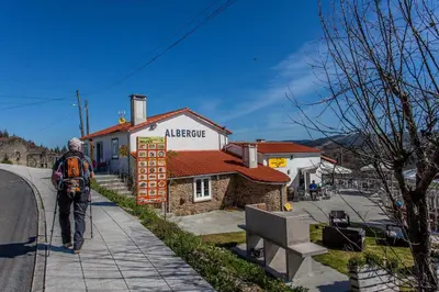 a man walking down a street next to a building at Albergue Milpés in Ribadiso