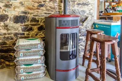 a stack of books next to a heater next to chairs at Albergue Milpés in Ribadiso