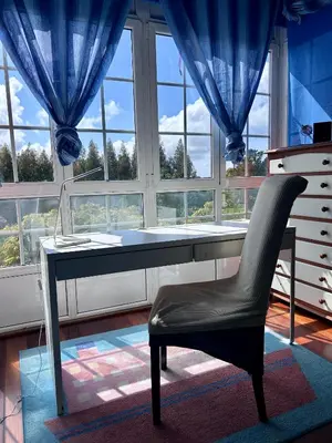 a desk and a chair in a room with windows at Los Cedros in Cabañas