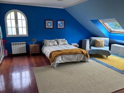 a blue bedroom with a bed and a chair at Los Cedros in Cabañas