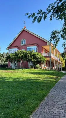 a large red house on a green field at Los Cedros in Cabañas